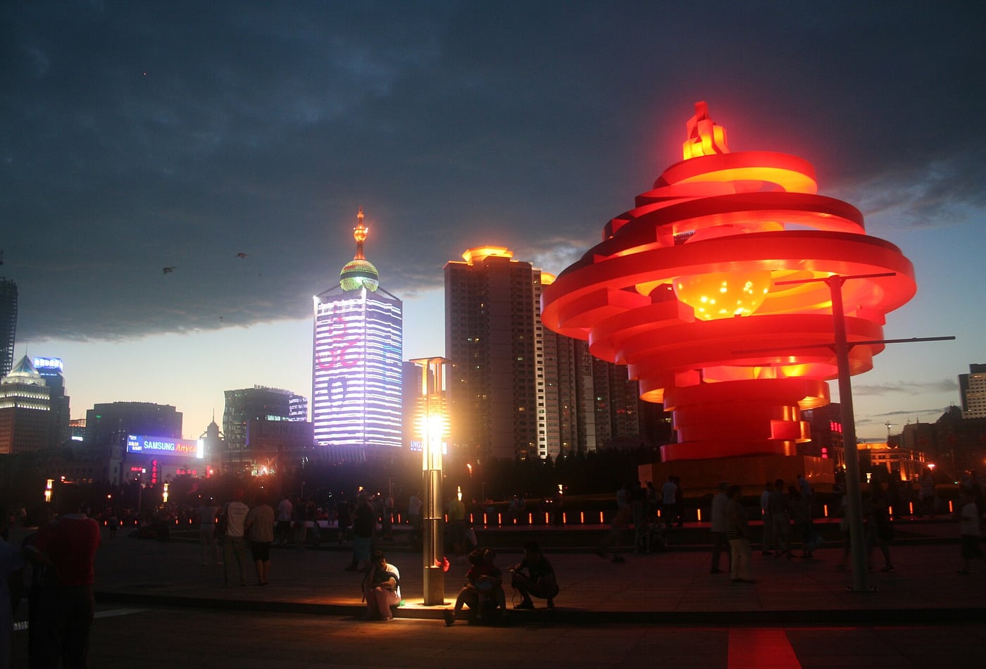 The red May Wind sculpture at May Fourth Square in Qingdao at twilight.