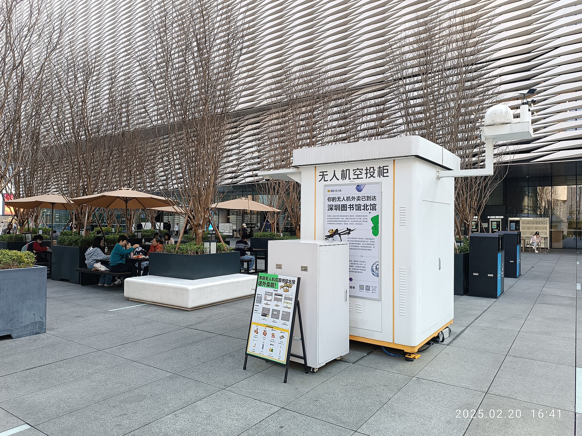 Drone delivery pickup cabinet and ordering sign on a Shenzhen plaza