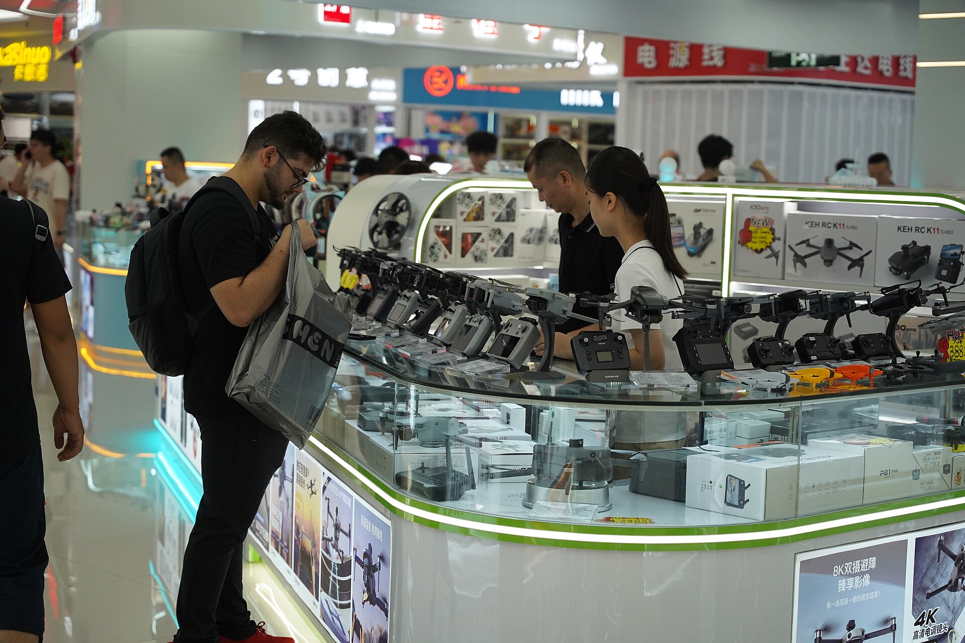 Traveler looking at camera drones inside Shenzhen Huaqiang Electronic World